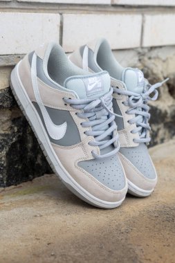Nike sb 'nin yakın çekimlerinde açık gri ve bej renkli spor ayakkabılar, tasarımlarını ve yerlerini beton bir basamağa sergiliyorlar.
