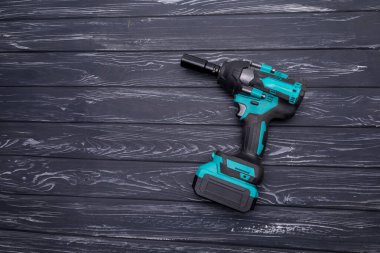 Turkuaz kablosuz çarpma anahtarı ve siyah ahşap tezgahın üzerinde birkaç parça var.