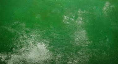 Yeşil bir yüzeyi kaplayan beyaz toz soyut bir doku oluşturuyor.