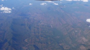 Rural small village in tropical forest mountain valleys of Southeast Asia aerial view from plane window