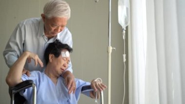 Hopeless injured wife on wheelchair in hospital very bad condition sad senior couple emotional support crying hugging