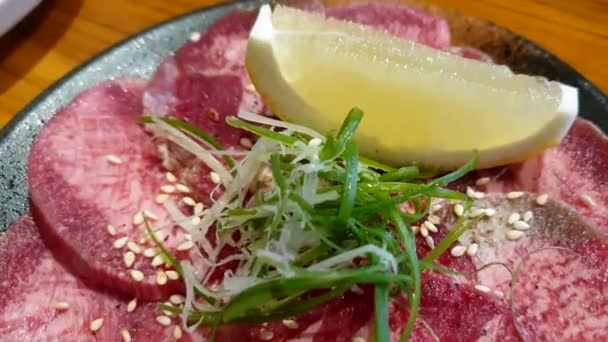 日本风格的龙涎香薄片牛肉舌根烤肉配柠檬绿色洋葱味道鲜美 — 图库视频影像