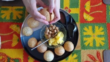 Panipuri Hint usulü abur cubur yiyen bir kadın bezelye patatesli ve baharatlı çıtır köfte yiyor.