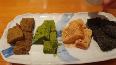 Japon tatlı Warabi mochi 'sinin üzerine soya fasulyesi hojicha yeşil çay dök.