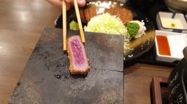 Japon yemek takımı gyukatsu sığır eti aslanı. Kabuklu tonkatsu ile kızartılmış. Müşteri pişirme seviyesini ayarlamak için et ızgara yapıyor.