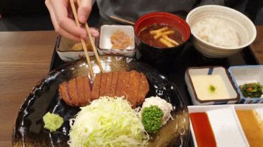 Japon yemek takımı gyukatsu sığır eti aslanı. Kabuklu tonkatsu ile kızartılmış. Müşteri pişirme seviyesini ayarlamak için et ızgara yapıyor.