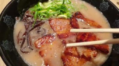 Chopsticks Japon tonkotsu ramen yiyor kalın kremalı domuz kemiği çorbası ve chashu Tokyo sokak eriştesi.