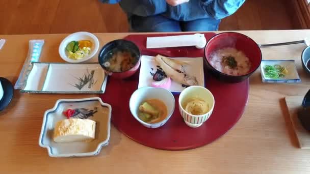 清早早餐日本菜设置在龙眼粥烤鱼蛋等配菜上 — 图库视频影像
