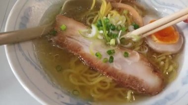 Hokkaido 'nun ünlü tuzlu domuz çorbası çorbası shio ramen dilimi ızgara domuz eti ve haşlanmış yumurta yavaş çekim