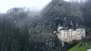 Slovanya 'daki tarihi Predjama mağara şatosu. Yağmurlu, soğuk, kış sisi manzarası.