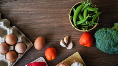 Flay yemek pişirirken sebze brokoli yumurta biber bezelye sarımsak arkaplanı ahşap dokusu metin kopyalama alanı