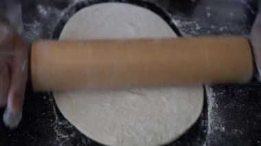 İtalyan şef pizza hamuru hazırlıyor ve yuvarlanıyor.