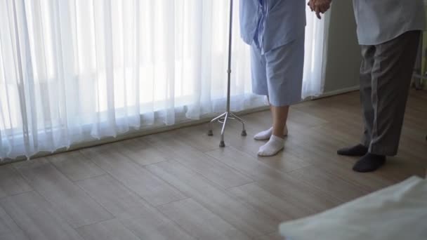 アジアの年長の夫は 妻が歩く練習スティックを使用して足の怪我4Kを回復するのに役立ちます — ストック動画