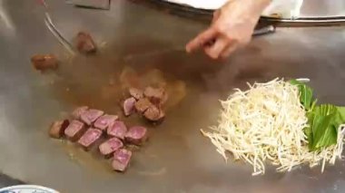 Şef, Teppanyaki metal tabağında wagyu kobe bifteği dilimliyor. Sebze 4k ile.