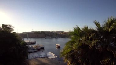 Aswan 'daki Nil nehri limanındaki Felucca teknesine binmek kum tepeleri ile günbatımı 4k