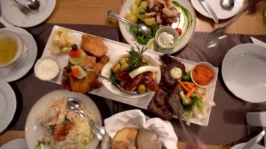 Tatil ziyafetini birlikte yiyen aile ve arkadaşlar batı yemekleri biftek, deniz ürünleri ve salata ev partisi.