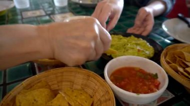  Meksika yemeği yiyen aile elleri mısır cipsi sosu ve avokado sosu.