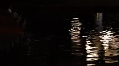 Geceleri karanlık su dalgalanması arka planda küçük ışık yansıması 4k
