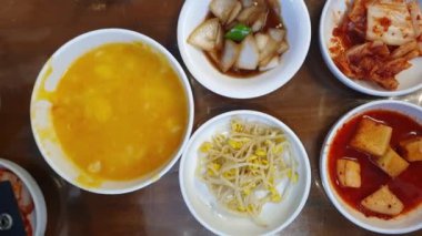 Elle yenilen Kore yemeği banchan mezeleri ve Hobakjuk kabak lapası. Yemek çubuklarıyla üst manzara.