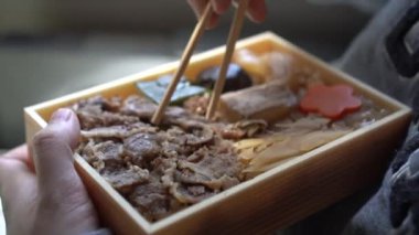 Kadınlar yemek çubukları ile Japon bifteği yiyorlar. Japon tren taşıma kültüründe bento gyudon yiyorlar.