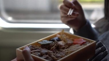 Kadınlar yemek çubukları ile Japon bifteği yiyorlar. Japon tren taşıma kültüründe bento gyudon yiyorlar.