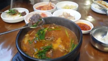 Dondurma çorbası içerken kan sosisi ve domuz iç organı güveç baharatlı çorba Kore yemeği ağır çekim