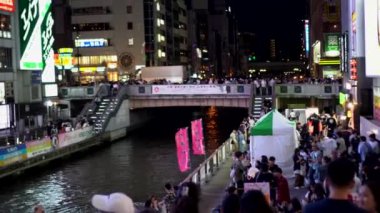 Osaka, Japonya -15 Nisan 2023: Glico imzası Osaka Dotonburi bölgesi dönüm noktası kamera manzaralı turist, kanal ve reklam panoları