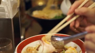 Yaşlılar Japon restoranında çubuklarla erişte yiyorlar.