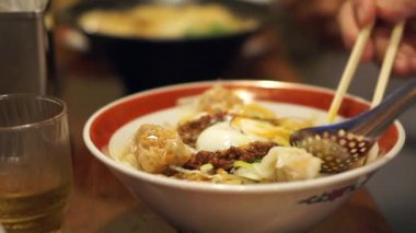 Yaşlılar Japon restoranında çubuklarla erişte yiyorlar.