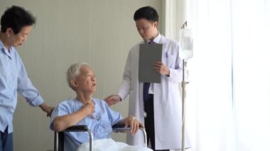 Asyalı doktor yaşlı tekerlekli sandalye hastalarını kontrol ediyor.