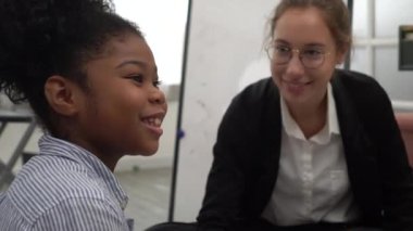 Neşeli Afrikalı etnik çocuk ve Kafkas öğretmeni mutlu çeşitlilik okulu ortamında