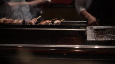 Japon yemeği yakitori tavuk şişleri izakaya aşçısı mangal kömürü ateşiyle pişiriyor..