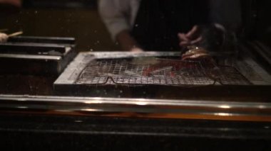 Japon yemeği yakitori tavuk şişleri izakaya aşçısı mangal kömürü ateşiyle pişiriyor..