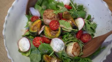 Kürekler yeşil salatayı balkabağıyla karıştırıyor domates pancarı ve midye sağlıklı yiyecekler.