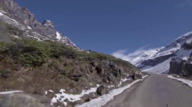 Önde giden plakalı araç karlı arazide dağlara doğru yol alıyor.