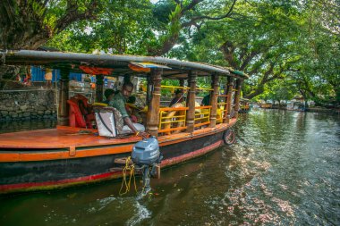 Alappuzha Alleppey Kerala 'da yüzen evin kullanıldığı gölün üzerini ağaç dalları kaplıyor.