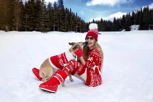美丽的女人穿着红色的圣诞服装 和她的狗在雪地里玩耍 在山中的冬季风景里 寒假圣诞节的概念 — 图库照片