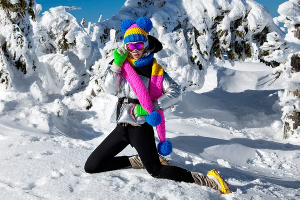stock image Winter fashion. Beautiful girl is wearing jacket, ski goggles and colorful winter hat and is posing on mountains background. Szrenica, Poland. Mountain travel.