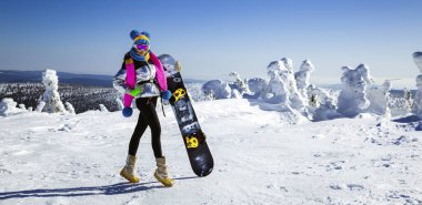Kız snowboardcu kayak merkezinin tadını çıkarıyor. Kış kıyafetli güzel bir kadın dağlarda snowboard ile poz veriyor. Kış sporları. Snowboard..