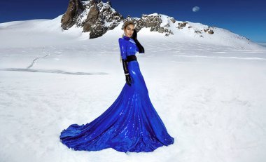 Beautiful young girl in a blue sequin long winter gown dress in the snow. Hollywood chic, fashion, beauty. Elegance.