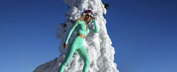 冬のファッション 美しい女性はセクシーな冬服や冬の帽子やカラフルなブーツを着ており 山の上に雪の中でポーズをとっています 屋外撮影 — ストック写真