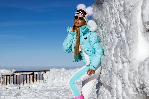 美丽的女模特穿着性感的冬衣 头戴冬季帽子 脚穿五彩缤纷的靴子 躺在山上雪地里 冬季时尚 户外运动 — 图库照片
