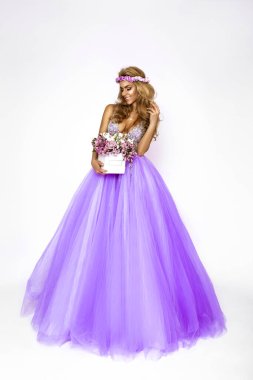 Zarif bahar elbisesi ve çiçek tacıyla güzel doğal bir kadın elinde bir buket bahar çiçeği tutuyor..