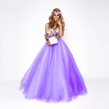 Zarif bahar elbisesi ve çiçek tacıyla güzel doğal bir kadın elinde bir buket bahar çiçeği tutuyor..