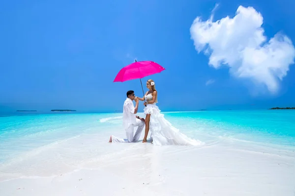 여름의 아름다운 드레스와 분홍빛 우산을 부부가 몰디브의 해변에 몰디브의 해변에서 — 스톡 사진