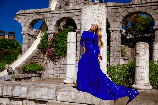 穿着蓝色长袍的优雅优雅优雅的女人 穿着华丽的晚礼服 躺在游泳池边的豪华度假胜地室外 — 图库照片