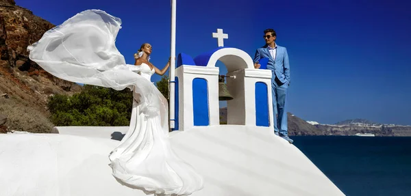 サマー 美しい幸せな若いカップルの花嫁と結婚式の服で成長は サントリーニ島のフィラの3つの鐘の教会の近くにポーズしています ギリシャの結婚式 — ストック写真