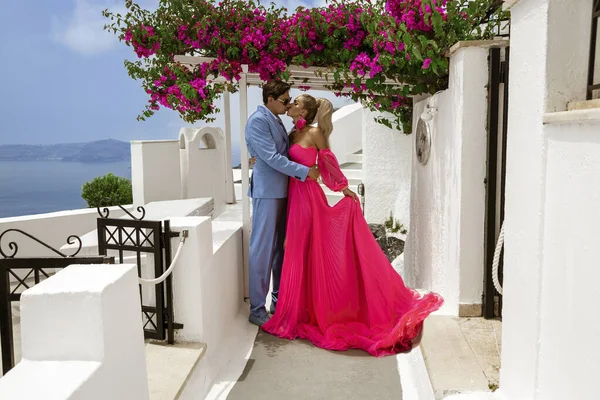 Summer love. Beautiful happy young couple in elegant wedding clothes is posing in Fira in Santorini. Engagements and wedding in Santorini island of Greece.
