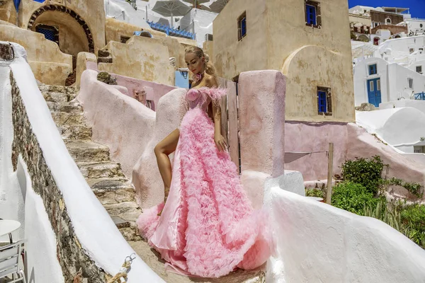 ピンクの長いロマンチックなドレスの美しい女性は サントリーニ島のオイアでポーズしています 素晴らしいロングドレスの女性モデル クチュール — ストック写真