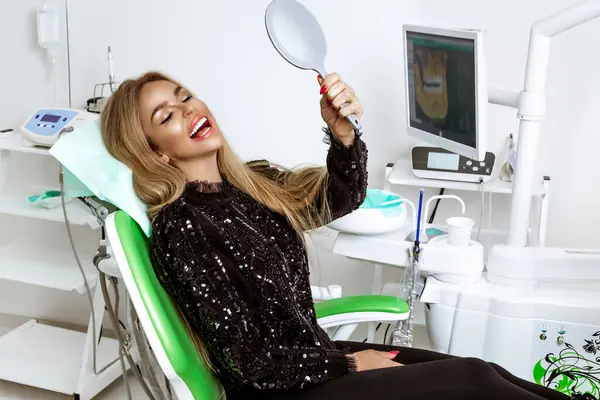 Beautiful happy woman sitting in the dentist chair and enjoying her new smile. Porcelain veneers.